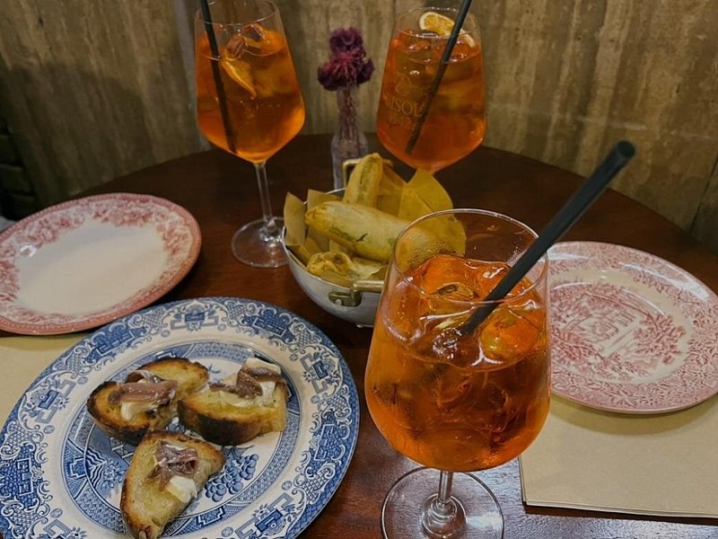 An aperitivo laid out: spritz, crostini and crisps
