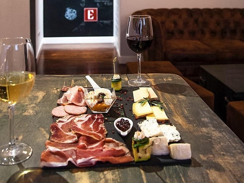 A board of cured meats and cheeses set out with wine