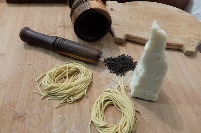 Fresh pasta, a wedge of pecorino and black peppercorns on a board