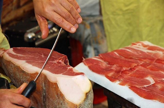 Prosciutto being sliced by hand from the bone