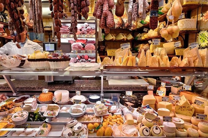 A Roman market counter stacked with cheeses, cured meats and prepared food