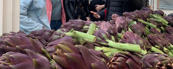 Romanesco artichokes piled on a market stall, stalks upward