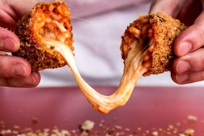 A supplì pulled open, the mozzarella stretching between the two halves